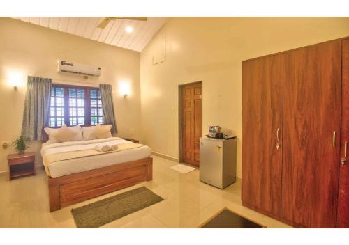 a bedroom with a bed and a refrigerator in it at Portu Stay Goa in Vagator