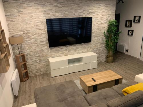 a living room with a television on a brick wall at T2 Cosy - 70m2 au Coeur de ville in Graulhet