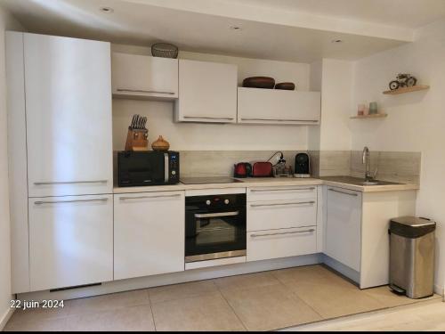 a kitchen with white cabinets and a microwave at Appartement Cosy en plein centre historique de Fréjus in Fréjus