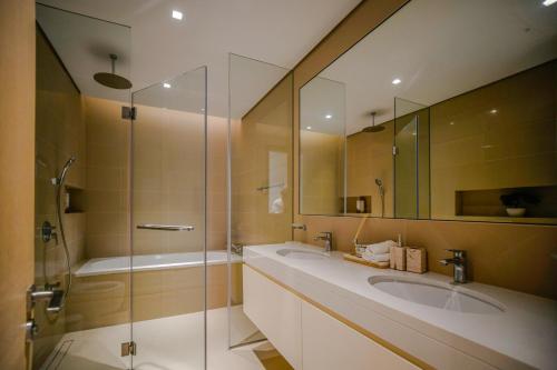 a bathroom with two sinks and a glass shower at Juman flat Marina and Sea view in Ḩayl Āl ‘Umayr