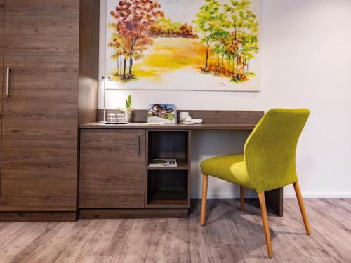 a desk with a green chair in a room at VitalZeit Hotel Weber in Bad Schönau