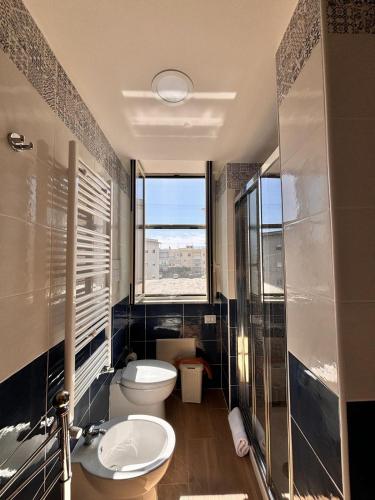 a bathroom with a toilet and a sink and a window at Little House Galileo in Reggio di Calabria