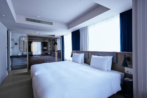 a bedroom with a large white bed and a bathroom at NOHGA HOTEL UENO TOKYO in Tokyo