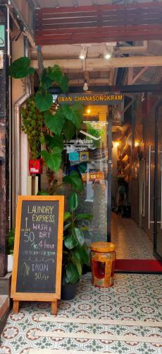 un magasin avec une enseigne devant une plante dans l'établissement Bann Chana BKK, à Bangkok