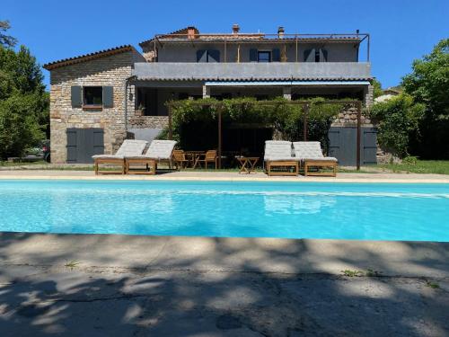une maison avec une piscine et deux chaises longues dans l'établissement L'Auberge du Ranc, à Saint-Sèbastien