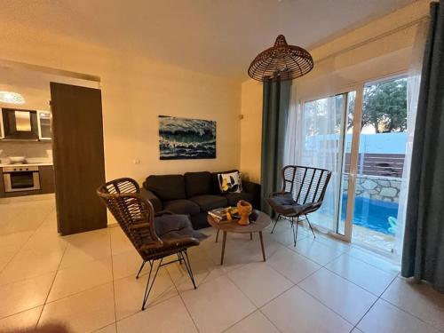 a living room with a couch and chairs and a table at Colibri seafront villa with pool in Nopíyia