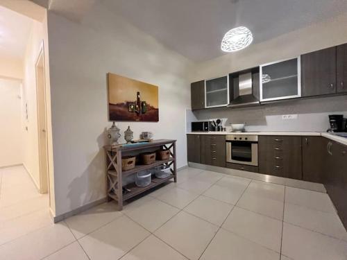 a kitchen with brown cabinets and a white tile floor at Colibri seafront villa with pool in Nopíyia