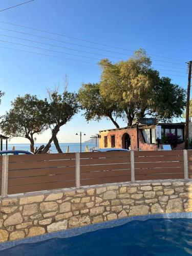 a wooden fence next to a swimming pool with trees at Colibri seafront villa with pool in Nopíyia