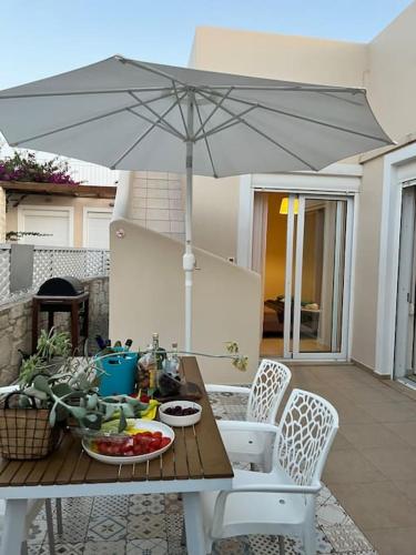a table with an umbrella on a patio at Colibri seafront villa with pool in Nopíyia