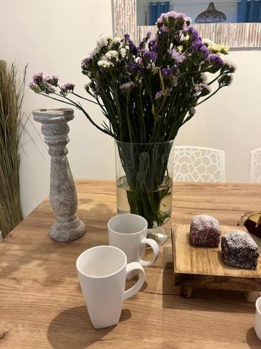a wooden table with cups and a vase with purple flowers at Colibri seafront villa with pool in Nopíyia
