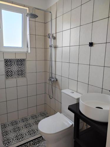 a bathroom with a toilet and a sink and a window at KROKOS house 2 in Aliveri