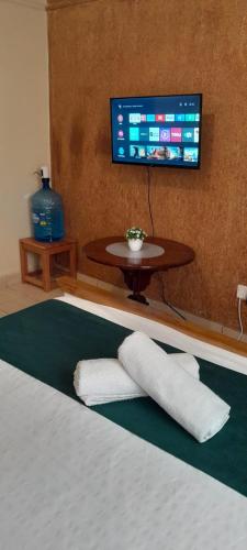 a bed with a table and a tv on a wall at Studio Apartment near the Airport in Nairobi
