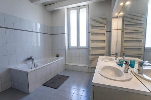 - une salle de bains blanche avec deux lavabos, une baignoire et une chambre dans l'établissement Maison familiale avec grand jardin, 2min de la mer, à Marseille