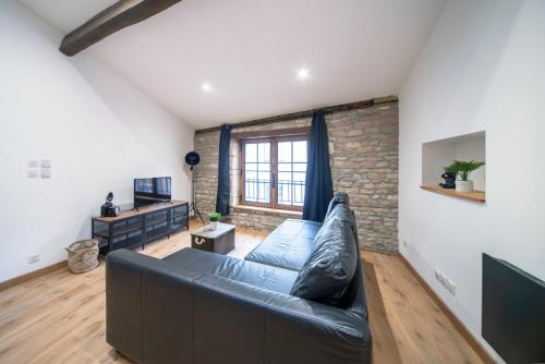 a living room with a leather couch and a brick wall at MyAppart71 - La préfecture - Appartement en Coeur de Ville in Mâcon