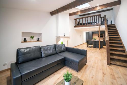 a living room with a black leather couch and stairs at MyAppart71 - La préfecture - Appartement en Coeur de Ville in Mâcon