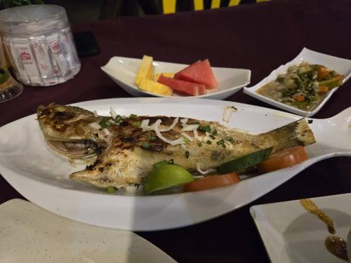 a plate of fish with vegetables and fruit on a table at Mama's Chalet Pulau Perhentian Besar in Perhentian Island