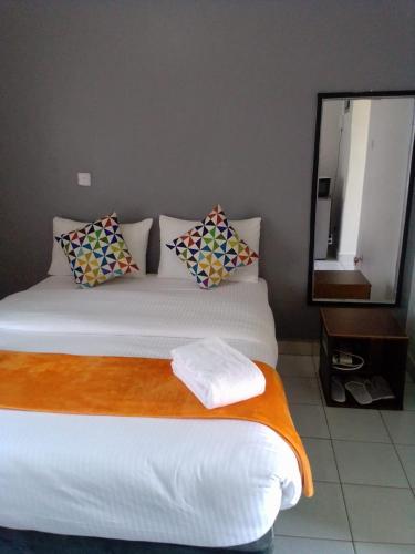 a bedroom with a white bed with pillows and a mirror at Studio Apartment near the Airport in Nairobi