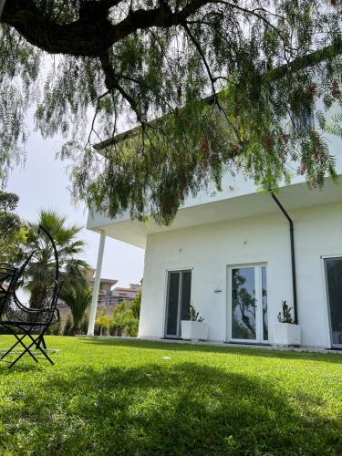 a white house with a bench in the grass at Appartamento Da Maria in Caulonia Marina