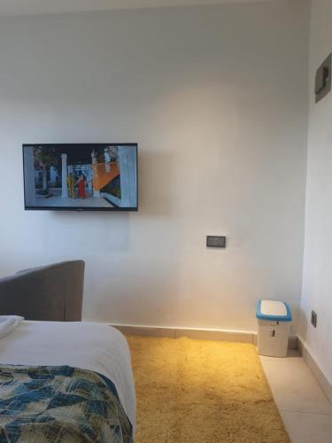 a bedroom with a tv hanging on a white wall at Studio Apartment near the Airport in Nairobi
