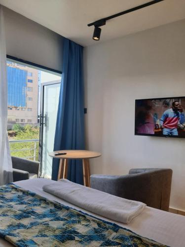 a room with a bed and a table and a window at Studio Apartment near the Airport in Nairobi