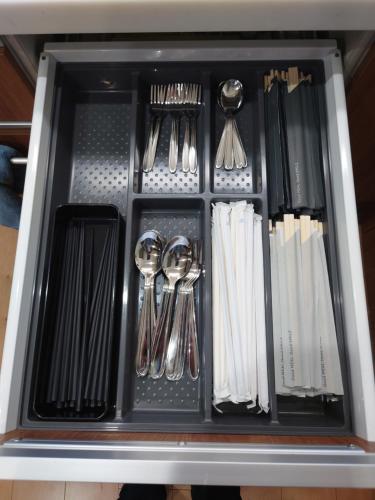 a drawer filled with utensils in a cabinet at ゲストハウス　風の丘 in Aji