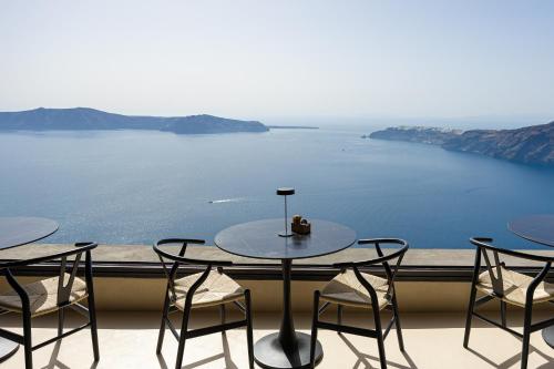 a table and chairs on a balcony with a view of the water at Caldera's Memories in Imerovigli