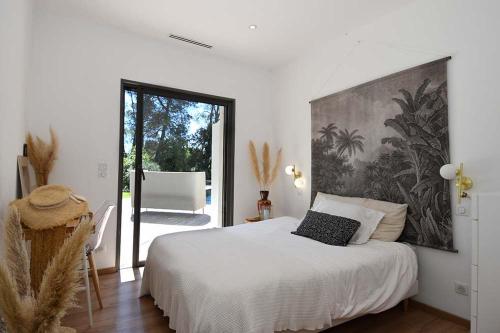 une chambre avec un lit blanc avec un tableau sur le mur dans l'établissement Magnifique contemporaine avec couloir de nage 15X3,5, à Sommières