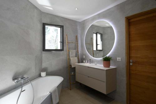une salle de bain avec une baignoire, un lavabo et un miroir dans l'établissement Magnifique contemporaine avec couloir de nage 15X3,5, à Sommières