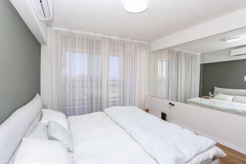 a white bedroom with two beds and a mirror at Mandarin Hotel 1BD Beach Flat in Jlil