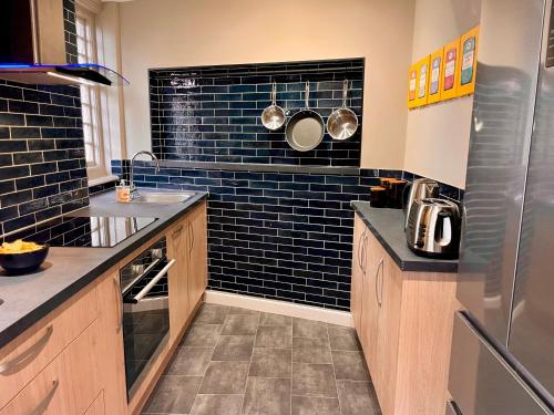 a kitchen with black tiles on the wall at Little Chelsea Garden Flat in Eastbourne