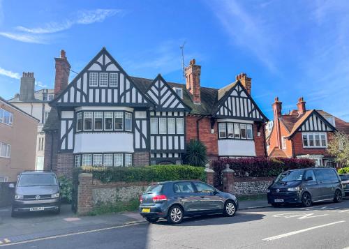 two cars parked in front of a black and white house at Little Chelsea Garden Flat in Eastbourne