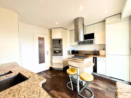 une cuisine avec des armoires blanches et un comptoir avec des tabourets dans l'établissement Le St Charles, à Saint-Laurent-du-Var