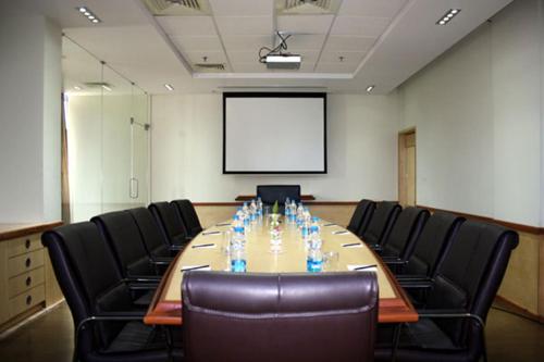 a conference room with a table and chairs and a screen at Royal Orchid Central Kireeti Hampi, Hospet in Hampi