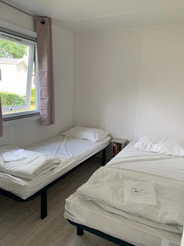 deux lits dans une chambre avec une fenêtre dans l'établissement Mobil Home 10 M et Mme COLAS, à Litteau