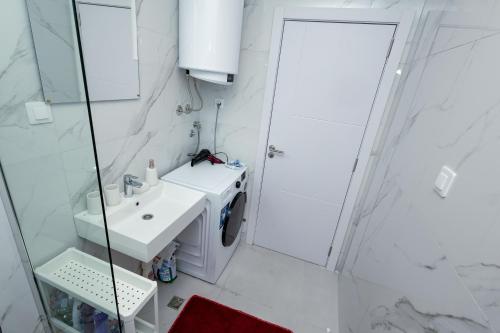 a white bathroom with a sink and a shower at Elegant Escape Podgorica in Podgorica
