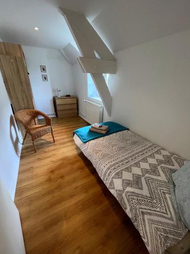 une chambre avec un lit et une chaise dans l'établissement Écurie des Charmes à 5 minutes de la plage, à Merville-Franceville-Plage