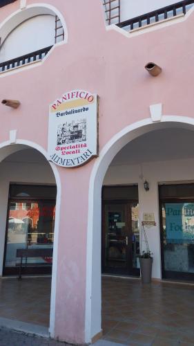 a pink building with three arches and a sign on it at Casa GIO' GIO' Borgo San Basilio in Marina di Pisticci