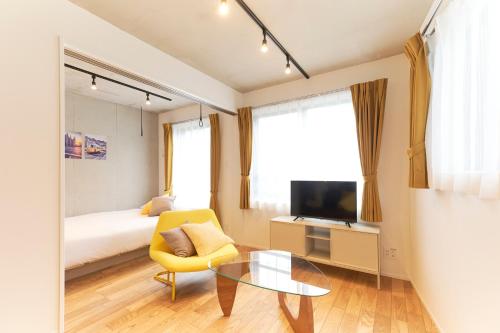 a bedroom with a bed and a table and a yellow chair at Frontier Comfort Kitaikebukuro by Tranova in Tokyo