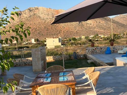 a patio with a table and chairs and an umbrella at Cindy Luxury Villas Crete GR in Stavros