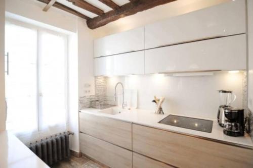 une cuisine avec des armoires blanches et un évier dans l'établissement Duplex Paris proche du Panthéon, à Paris