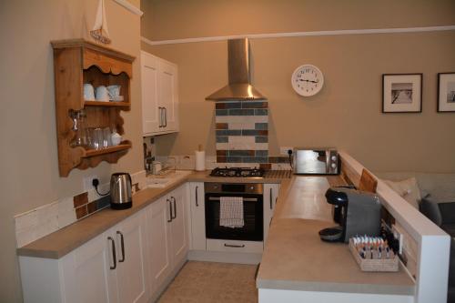 a kitchen with white cabinets and a stove top oven at The Fabulous Number Two Apartment a cosy coastal getaway in Cromer