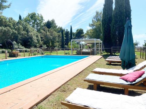 a swimming pool with lounge chairs and an umbrella at Relais Casale Il Poggetto - OLIVO 1 by Zoom In Earth in Cecina