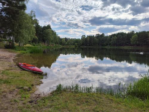 a red canoe sitting on the shore of a lake at Stacja Marylin in MaryLin