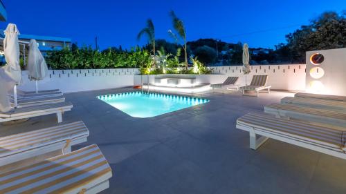 a pool with chaise lounge chairs and a swimming pool at Patricia Suites in Faliraki