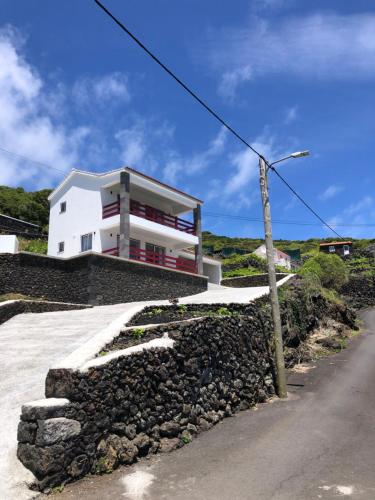 a white house on top of a rock wall at Casa da Baía da Feteira in Lajes do Pico