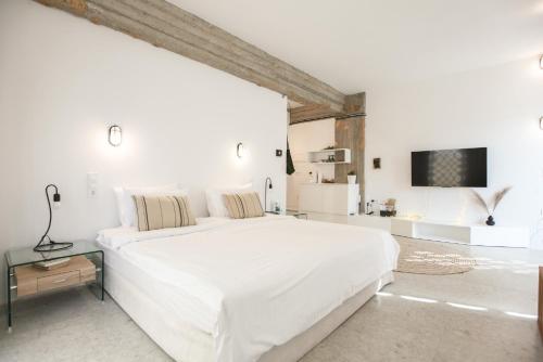 カランバカにあるConvent Apartments - Huge One Combinationの大きなベッドとテレビのある白い寝室
