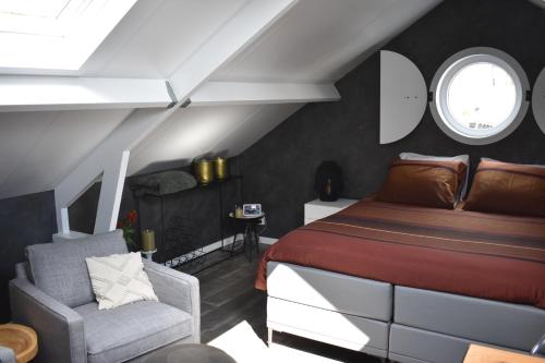 a bedroom with a bed and a chair at van Harte in Zeeland in Kamperland