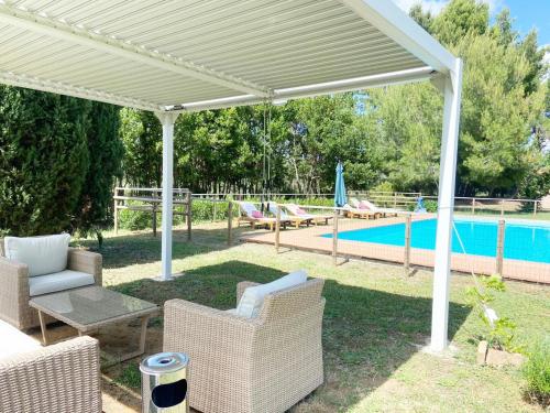 a white pavilion with chairs and a swimming pool at Relais Casale Il Poggetto - I PINI by Zoom In Earth in Cecina