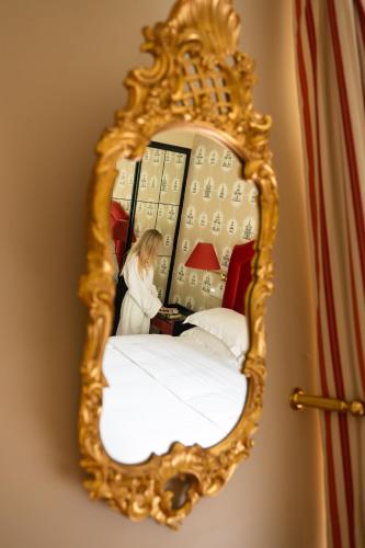 a woman sitting at a table in a mirror at NARUTIS Hotel - Small Luxury Hotels of The World in Vilnius