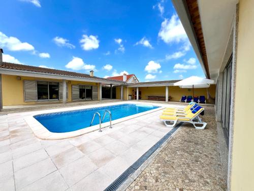 a swimming pool with a chair next to a house at A Casa do Pai Carlos in Salreu